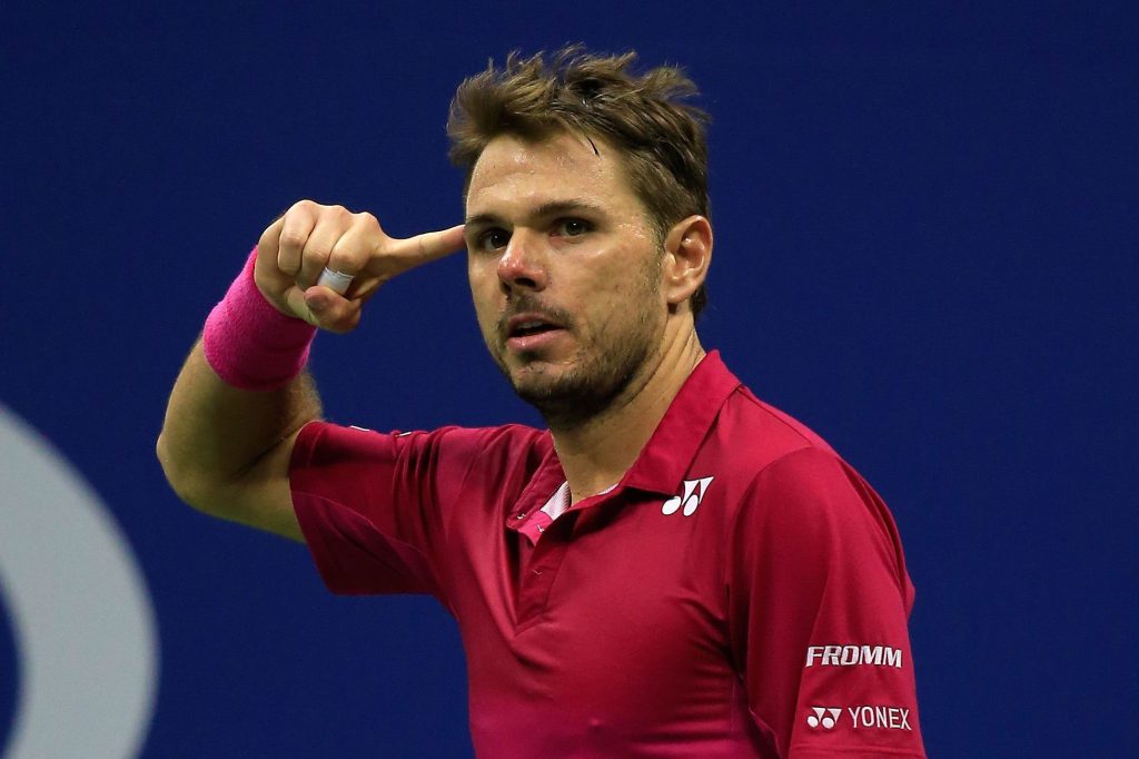 Jogador de tênis Stan Wawrinka, vestido com a camiseta vermelha, com o dedo apontado para a cabeça durante um jogo no US Open